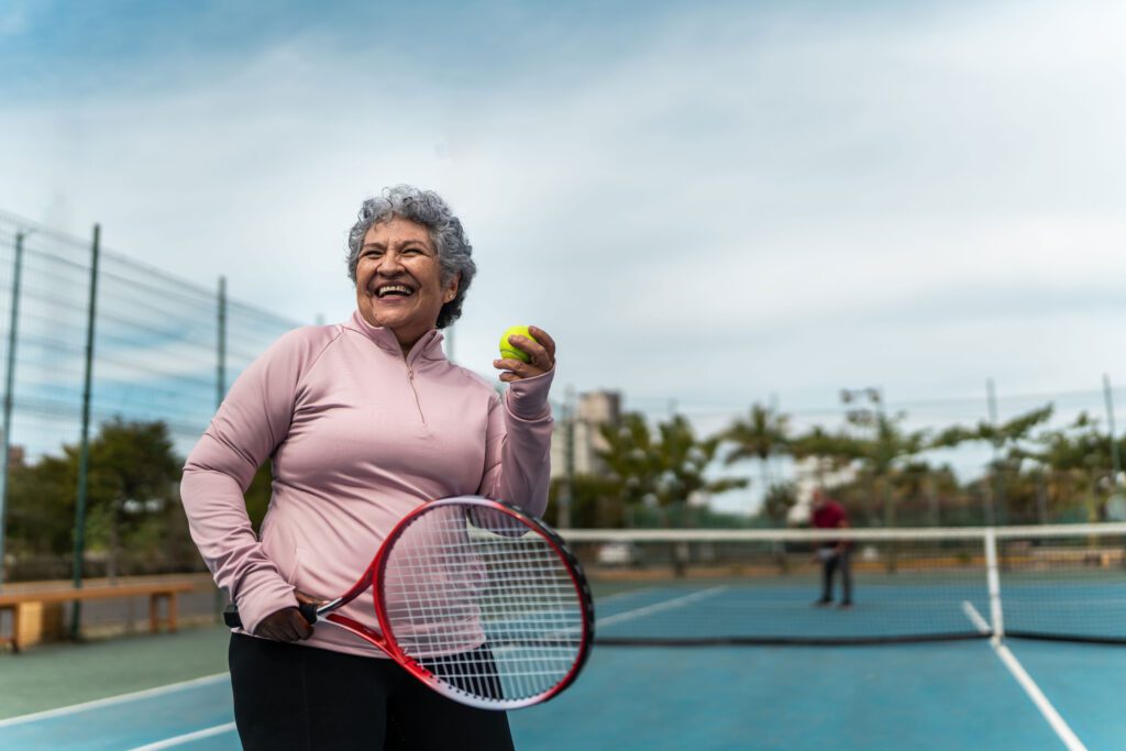 Senior woman smiling and playing tennis